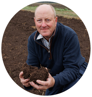A picture of Stephen Briggs, Cereals and Oilseeds sector council chair in a field holding some soil